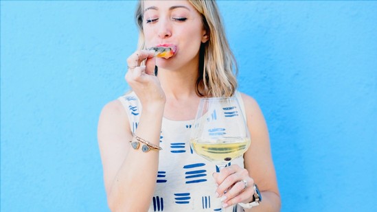 Woman eating a boozy popsicle and holding a glass of wine